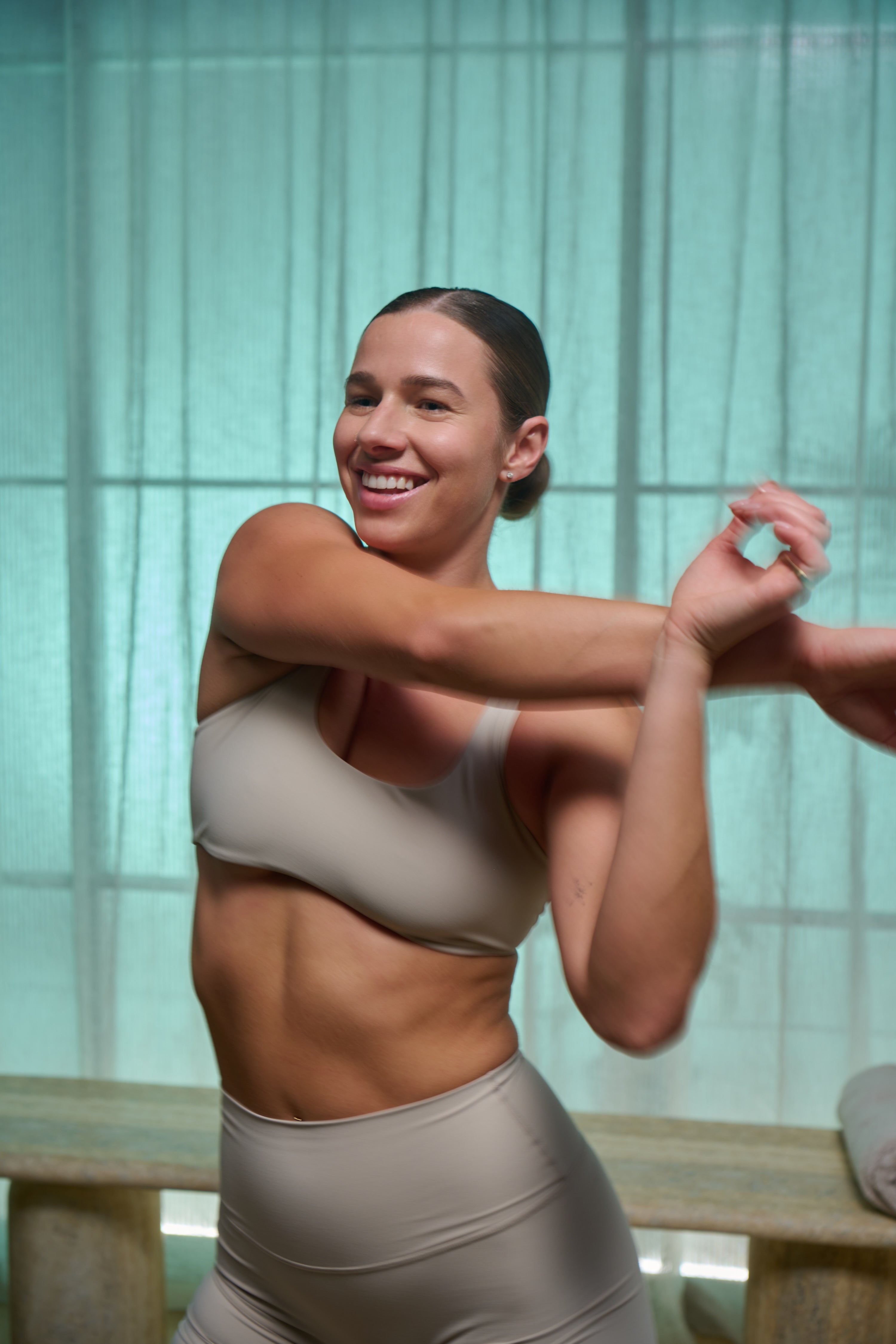 Woman in a beige outfit stretching with a blurred background
