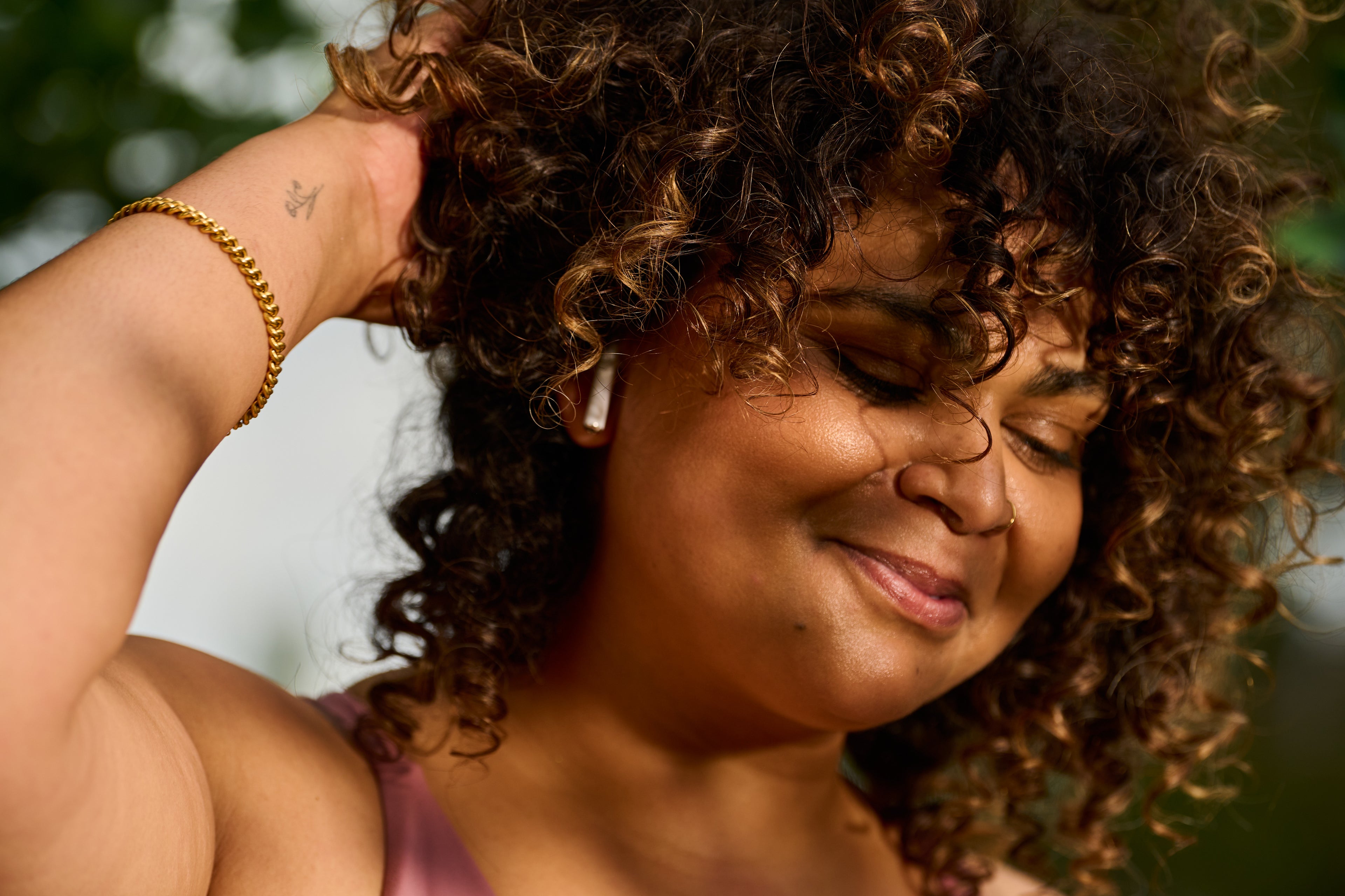 Woman with curly hair smiling outdoors