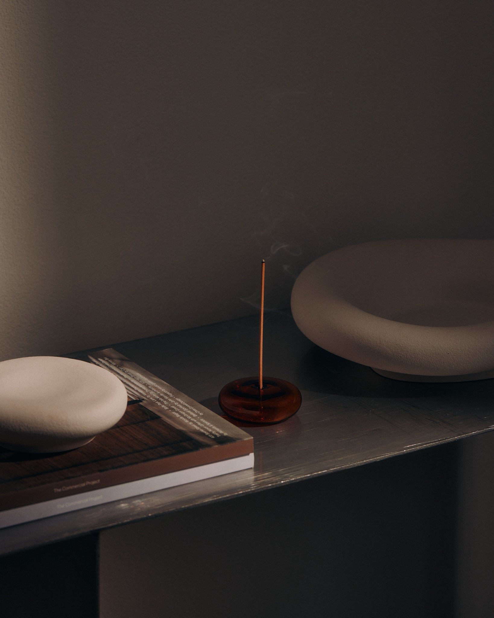 KIC incense stick burning on a shelf beside books and ceramic dishes