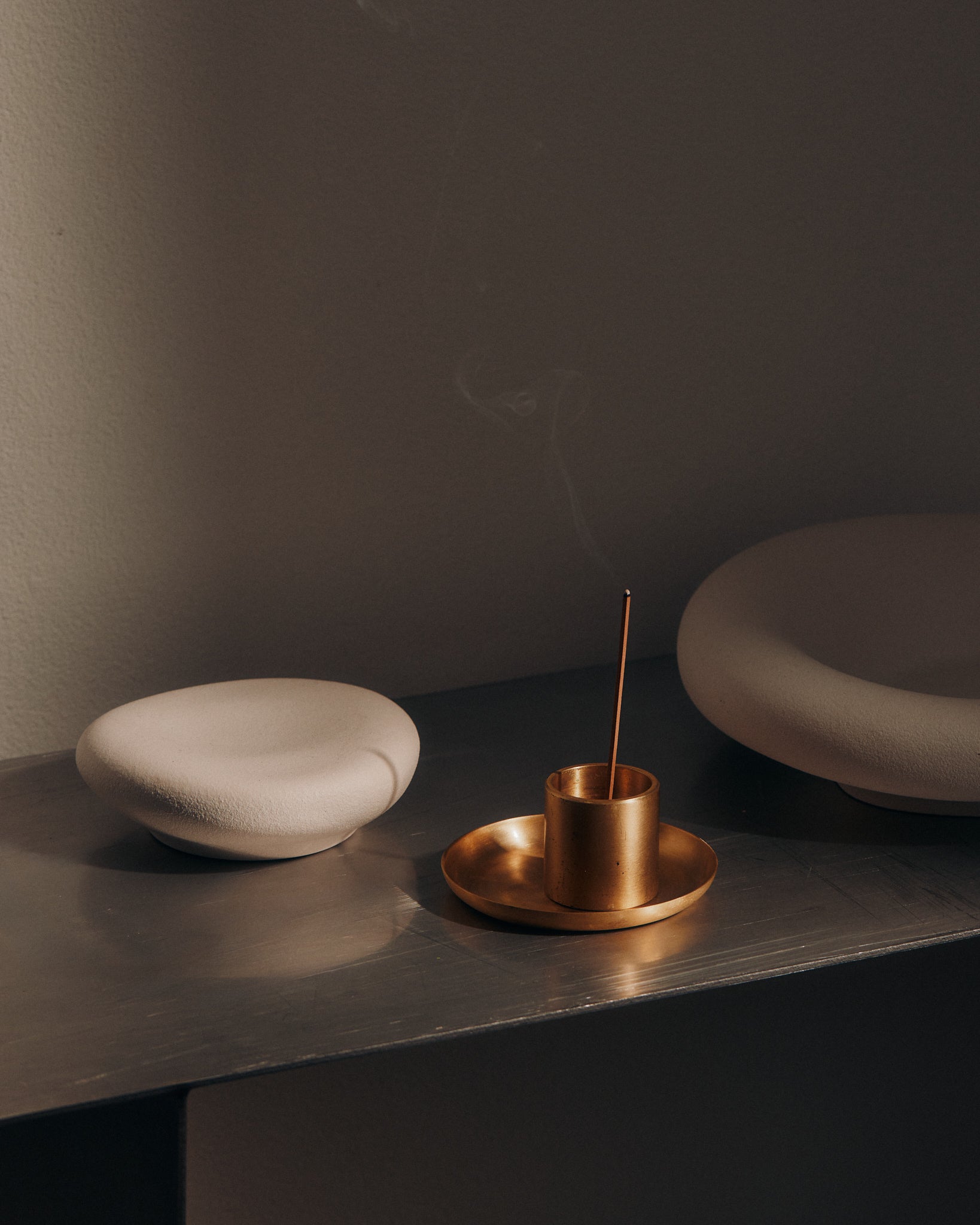 KIC incense stick burning on a shelf beside books and ceramic dishes