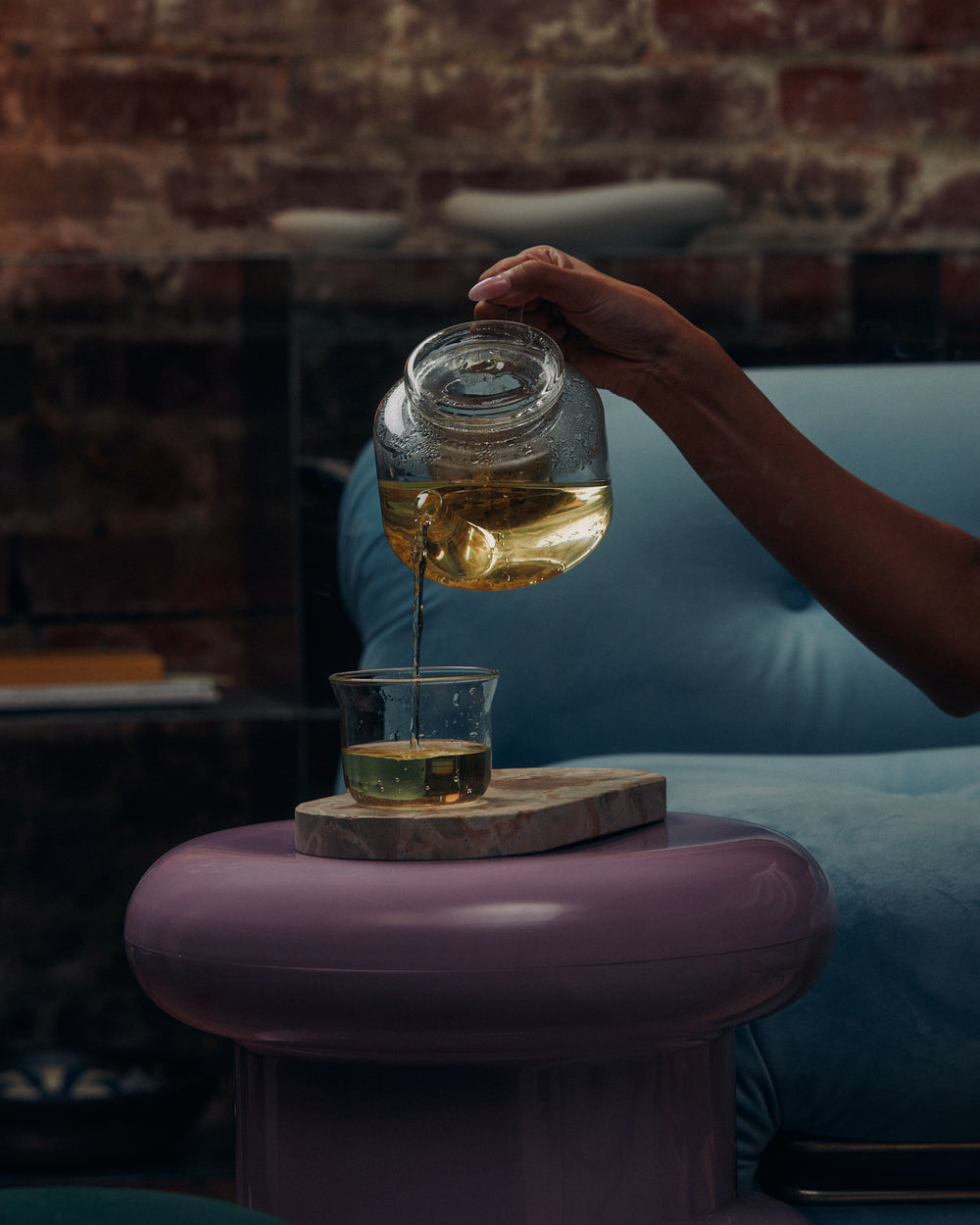 Woman pouring KIC herbal loose leaf tea from a glass jar into a mug at home
