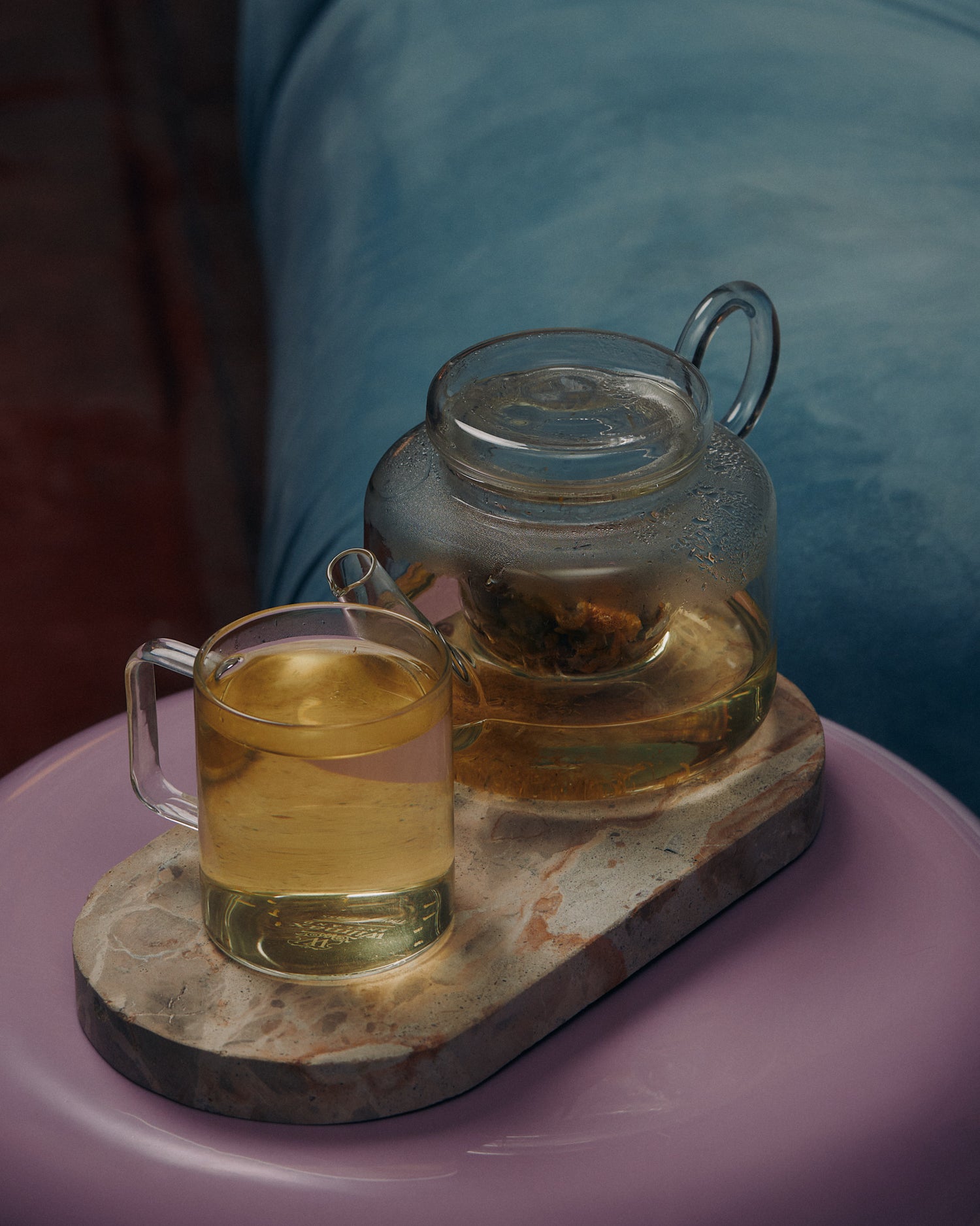 KIC herbal loose leaf tea in a glass teapot and mug on a marble tray
