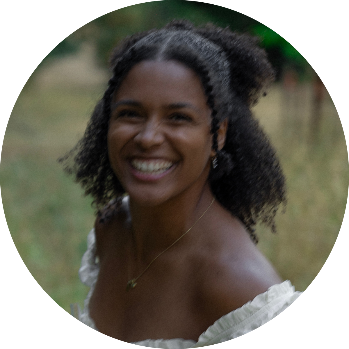 Picture of Anisa, a woman with braided hair, smiling outdoors