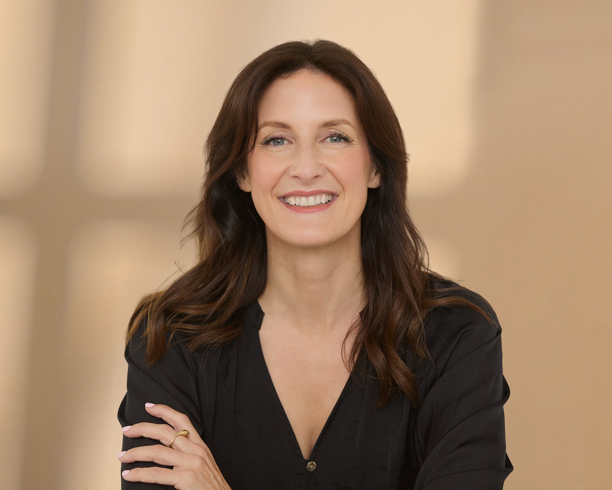 Janey smiling wearing a black shirt with her arms folded