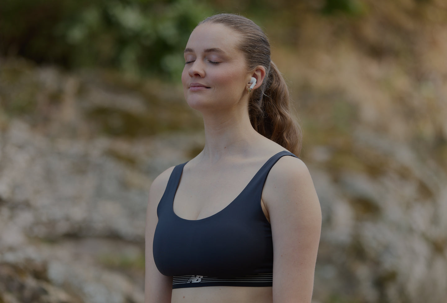 Laura, cofounder,  in a black sports bra standing outdoors with a blurred natural background