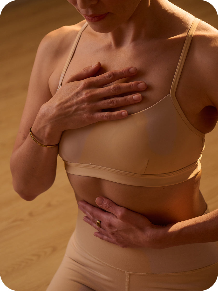 Woman wearing a beige sports bra and shorts set against a wooden background