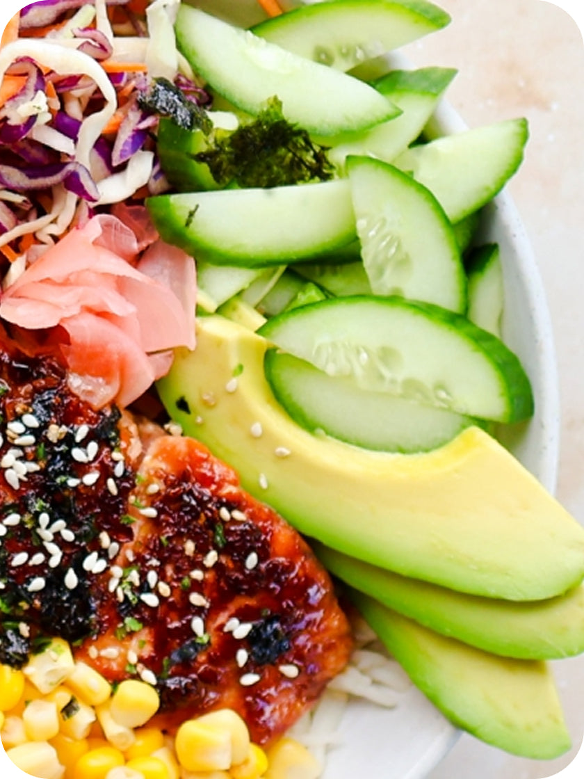 Plated dish with sushi, avocado, and vegetables on a white plate