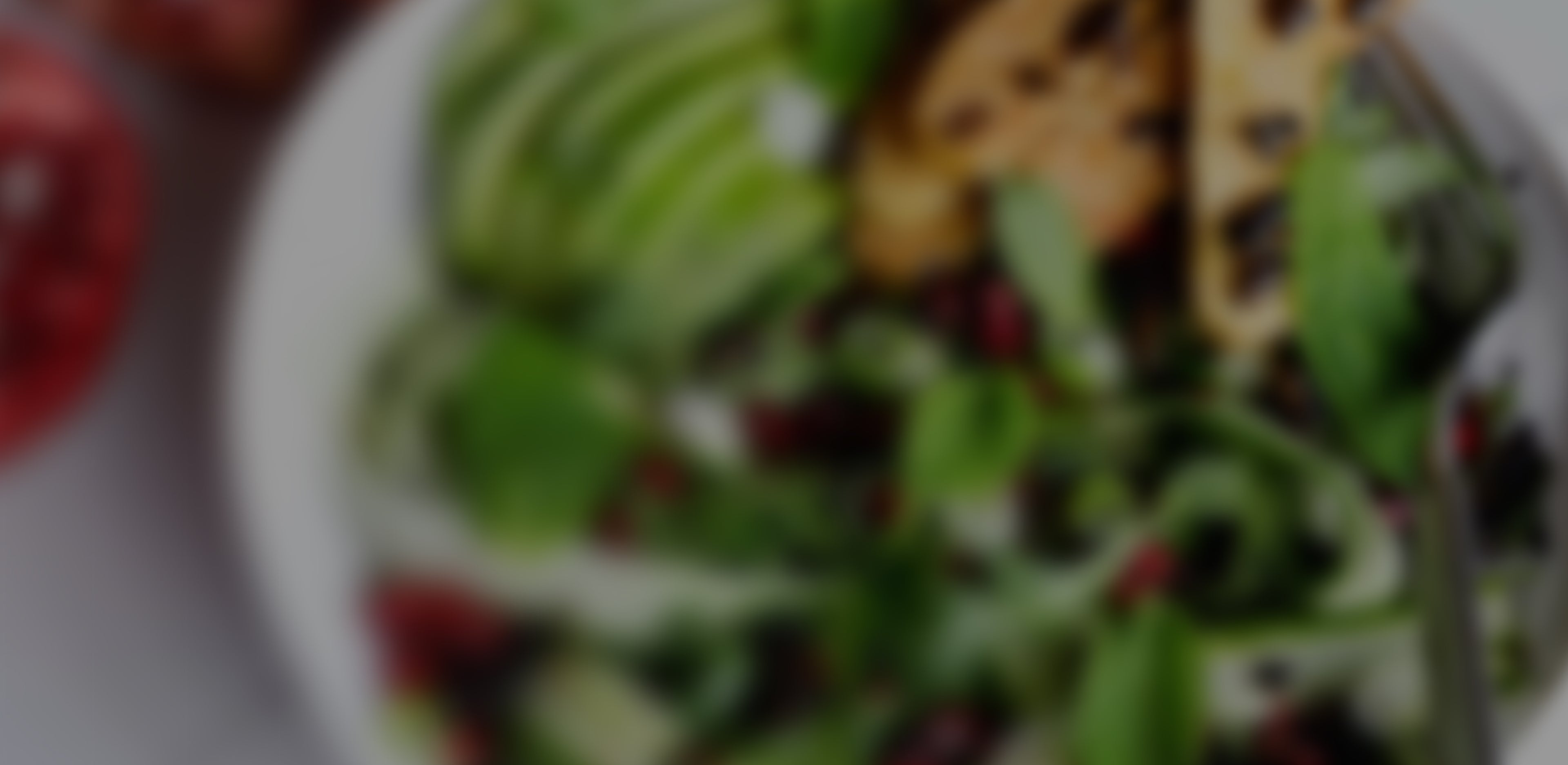 Blurred salad with greens, avocados, and possibly chicken on a plate.
