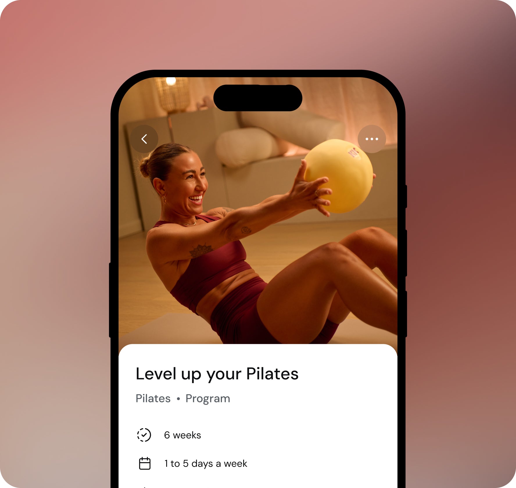Phone screen showing a Pilates program with a woman using a ball on a pink gradient background