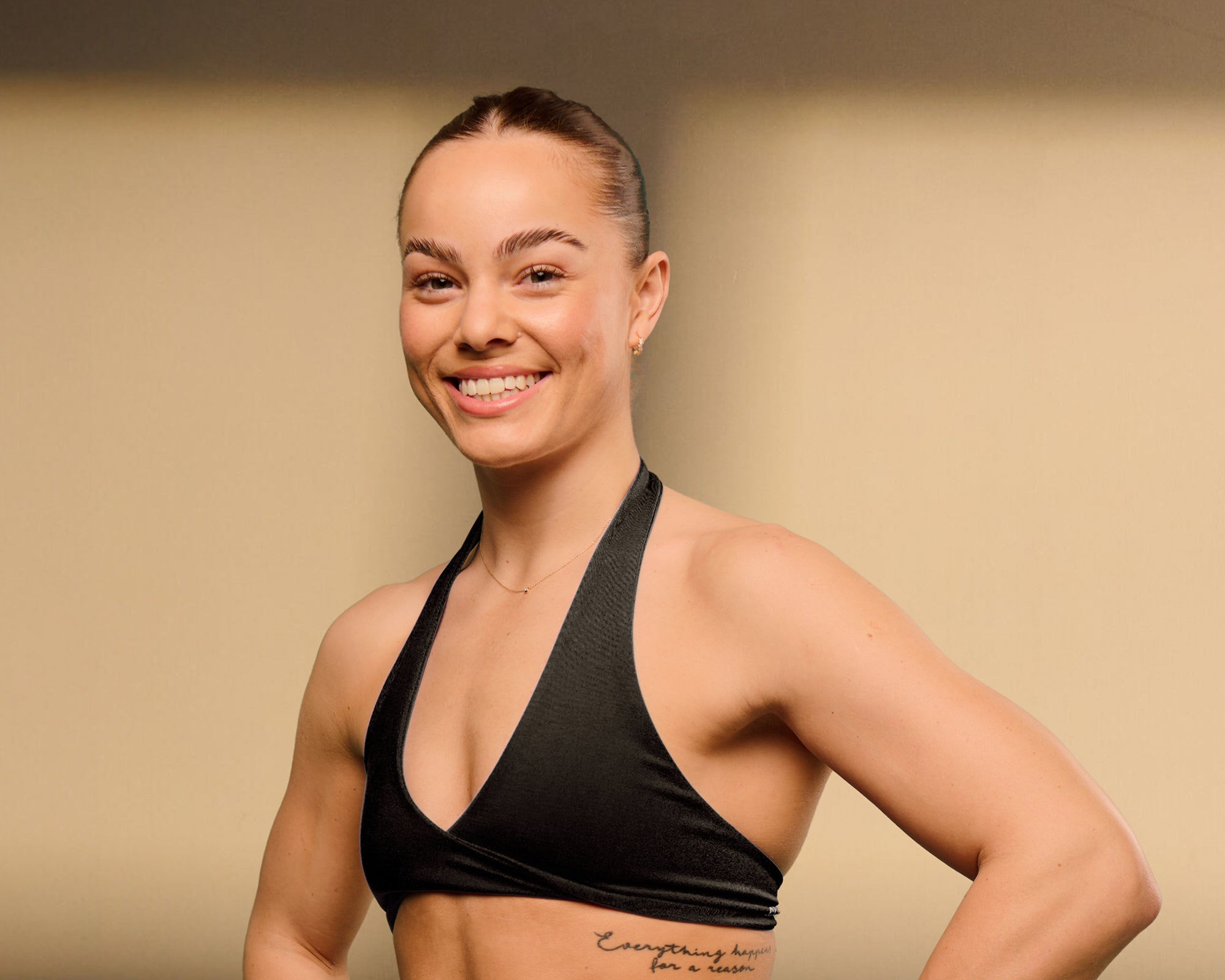 Woman wearing a black sports bra against a beige background