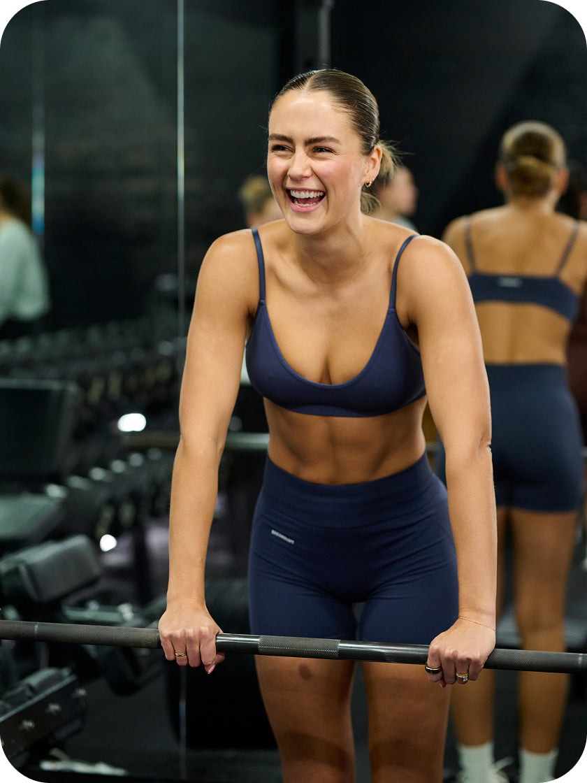 Woman exercising with a barbell in a gym setting